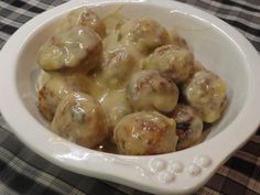 a white bowl filled with meatballs on top of a checkered tablecloth covered table