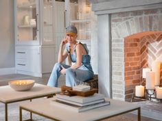 a woman sitting on a chair in front of a fire place with candles around her