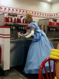 a woman in a blue dress standing at a counter