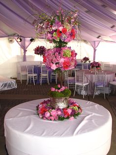 a table topped with a vase filled with pink and red flowers on top of a white round table