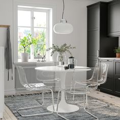 a white table and four chairs in a room with black cupboards on the wall