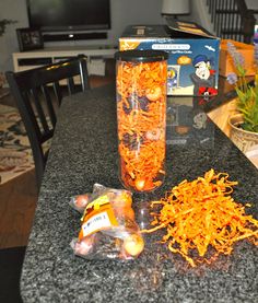 a counter top with orange shredded carrots on it next to a vase filled with flowers