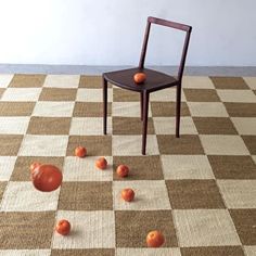 an empty chair sitting on top of a checkered floor with oranges scattered around it