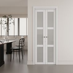 an empty kitchen with white walls and black chairs