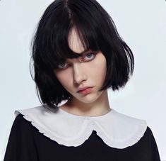 a woman with black hair wearing a black and white top