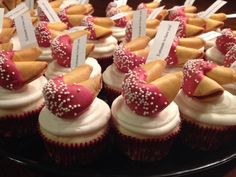 cupcakes with red and white frosting are arranged on a black platter