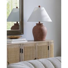 a lamp sitting on top of a wooden table next to a mirror and bookcase