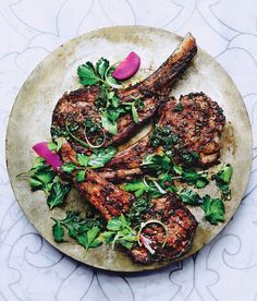 two steaks on a plate with greens and onions