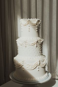 a three tiered white wedding cake sitting on top of a table