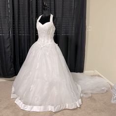 a white wedding dress on display in front of a black curtain