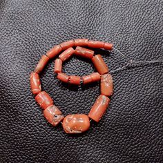 an orange beaded necklace on a black leather surface