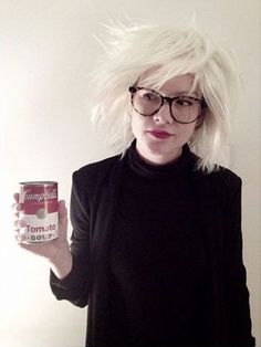 a woman with white hair and glasses holding a can