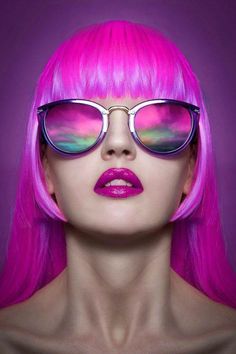 a woman with bright pink hair and sunglasses on her face, wearing purple lipstick to the side