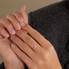 a woman's hands holding onto her wedding band and engagement ring, with one hand on the other