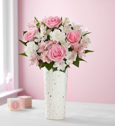 a white vase filled with pink and white flowers