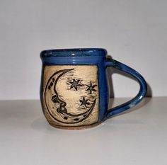 a blue and white coffee mug with stars on it's side sitting on a table