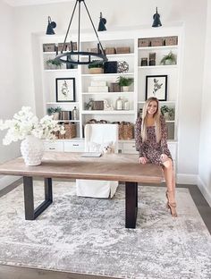 a woman sitting at a wooden table in front of a book shelf filled with books