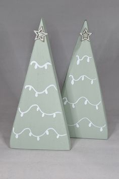 two small wooden christmas trees with silver stars on them, one is green and the other is white