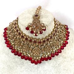 Beautiful antique gold necklace set with dazzling champagne zircon crystals and maroon stones. Plus maroon glass beads. Perfect bridal set Comes with matching jhumka earrings and matching tikka! Necklace 3 inch with adjustable string Earrings 2.25 Inch including jhumka length x 1 inch width Tikka 2.5 inch pendant plus 2 inch chain and 2 inch extender chain  Ready to be shipped ❤️ Gold Jeweled Beaded Necklace For Wedding, Gold Ruby Jewelry Sets For Wedding, Crystal Jeweled Bridal Necklace For Celebration, Gold Beaded Necklaces With Stone Work For Wedding, Gold Beaded Kundan Necklace, Heavy Gold Beaded Wedding Necklaces, Gold Jeweled Beaded Necklace For Celebration, Ornate Gold Necklaces With Stone Work, Gold Jeweled Bollywood Bridal Necklace