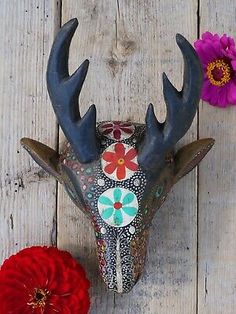 a deer's head with antlers and flowers on a wooden table next to it