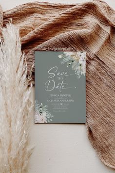 an elegant save the date card on top of a furnishy blanket with flowers