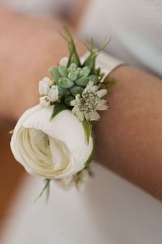 a close up of a person's arm wearing a flower wrist corsage