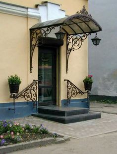 an entrance to a building with potted plants on the steps and a lamp post