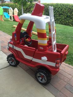 a toy fire truck is parked on the side of the road in front of some children's play equipment