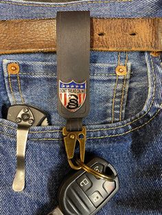 the car keys are attached to the back pocket of a pair of jeans with an american flag patch on it