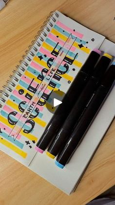 two pens sitting on top of a spiral notebook