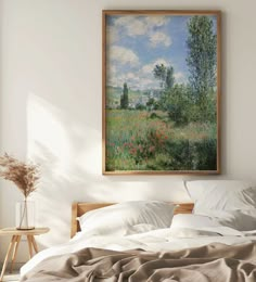 a painting hanging on the wall above a bed in a room with pillows and blankets