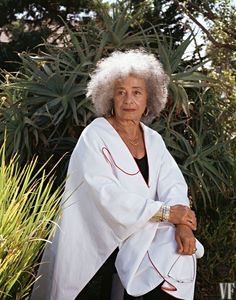 an older woman sitting in front of some plants