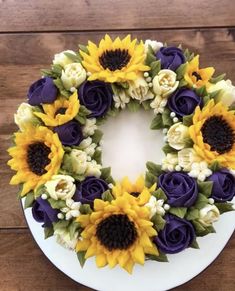 a white plate topped with a purple and yellow wreath covered in flowers on top of a wooden table