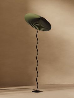 a floor lamp with a green shade on it's top and a black base