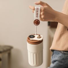 a person is holding a coffee cup with a keychain attached to the handle