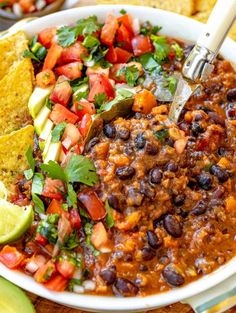 a white bowl filled with black bean chili and tortilla chips