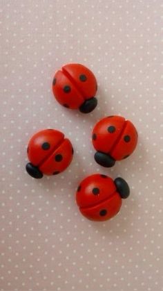 three red ladybugs sitting on top of a white table next to each other