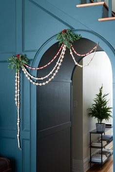 an arch decorated with christmas garland and greenery for the entrance to a room that has blue walls