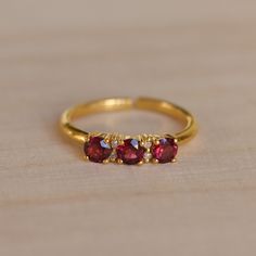 Dainty garnet and diamond gold ring.  Three gorgeous little faceted garnet gemstones flanked with two tiny diamonds besides the middle one and set in gold vermeil.  The open band is adjustable allowing it to be sized up a size. This ring makes such a special gift for that classic woman.  -  M A T E R I A L S - 925 Sterling Silver Gold plated  - G E M S T O N E   P R O P E R T I E S -  Diamond: love, strength, prosperity  Garnet  - S I Z E - Refer to https://pebblesandchance.com/pages/ring-sizing Gold Ruby Ring With Cubic Zirconia For Gift, Gold Garnet Open Ring, Gold Garnet Birthstone Ring Gift, Gold Ruby Crystal Ring With Birthstone, Adjustable Gold Ruby Ring Gift, Adjustable Elegant Ruby Ring, Gold Ruby Open Ring Birthstone, Gold Ruby Birthstone Open Ring, Garnet Birthstone Open Ring