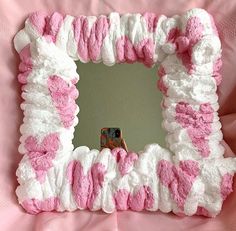 a pink and white pillow with a mirror in the shape of a heart on it