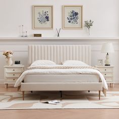 a white bed sitting in the middle of a bedroom next to two pictures on the wall