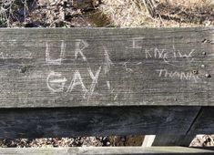 a wooden bench with graffiti written on it