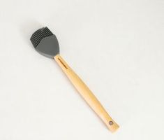 a wooden brush sitting on top of a white table next to a black and gray comb