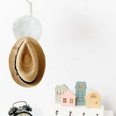 an alarm clock, toy houses and a hat hanging from a hook on the wall