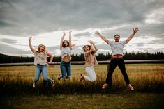 four people jumping in the air with their arms up