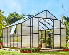 a small greenhouse in the middle of a yard with potted plants and flowers inside