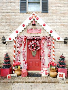 a red and white christmas door decorated with candy canes, poinsettis and decorations