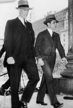 two men in suits and hats walking down the street