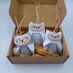 three stuffed owls in a cardboard box