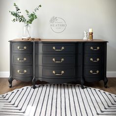 a black dresser with gold handles and knobs on the drawers in a living room